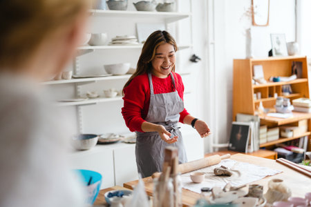 Smiling girl in apron and apron standing in potteryの写真素材