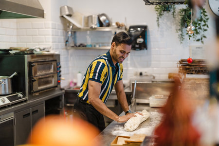 Smiling man kneading dough in the kitchenの写真素材