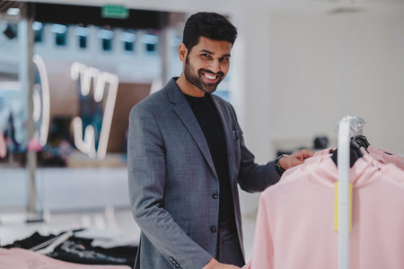 smiling indian man in suit looking at new clothes in boutiqueの写真素材