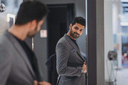 handsome young businessman looking at mirror in dressing roomの写真素材