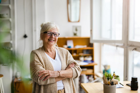 Portrait of smiling senior businesswoman standing with arms crossed in officeの写真素材
