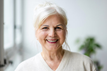 Portrait of a smiling senior woman looking at camera in the living roomの写真素材