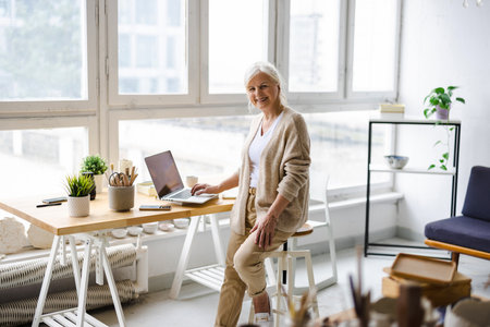 smiling senior businesswoman working with laptop at workplace in office, copy spaceの写真素材