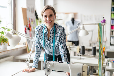 Portrait of a smiling female fashion designer working at her desk in a studioの写真素材