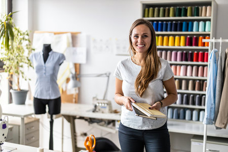 Portrait of a smiling female fashion designer standing in her studio.の写真素材