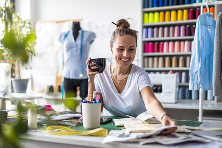 Portrait of smiling female fashion designer sitting at her workplace in studioの写真素材