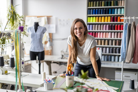 Portrait of happy female fashion designer standing at her workplace in studioの写真素材