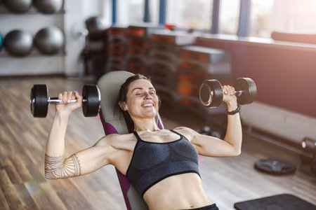 Young woman working out with dumbbells in the gym. Fitness and healthy lifestyle concept.の写真素材
