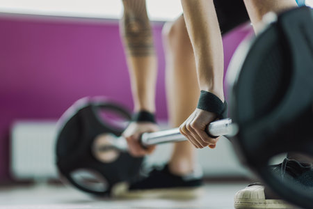 Close-up of woman lifting barbell in gym. Focus on handの写真素材