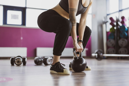 Young woman exercising with kettlebells in a gym. Focus on kettlebellの写真素材