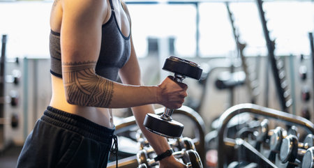 Close up of a young woman lifting dumbbells in a gymの写真素材