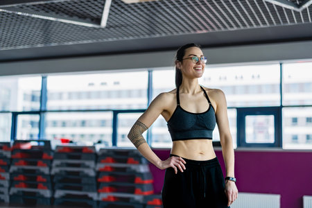 Portrait of a smiling young woman standing with arms crossed at the gymの写真素材