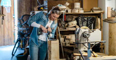 Carpenter working in her workshop. She is using a lathe and smiling.の写真素材