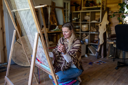 Beautiful young woman artist sitting on the wooden floor in her studio and drawing on canvas.の写真素材