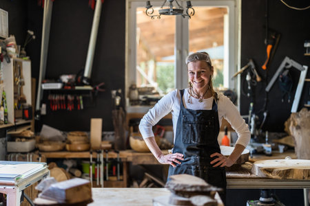 Portrait of a female carpenter standing in her workshop and smilingの写真素材
