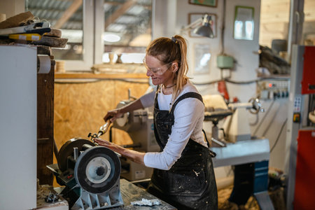 Portrait of a female carpenter working on a lathe in a workshopの写真素材