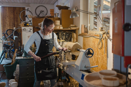 Portrait of mature female craftsman working on lathe in workshopの写真素材