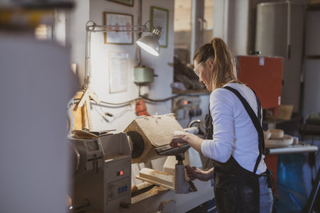 Female worker using lathe machine to cut paper in a factory workshopの写真素材