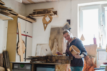 Carpenter working in his workshop, she is cutting wood with a knifeの写真素材