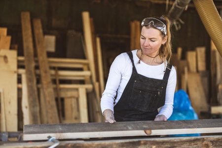 Portrait of female carpenter working with wooden planks in workshopの写真素材