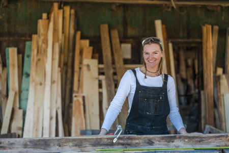 Portrait of smiling female carpenter working with wooden planks in workshopの写真素材