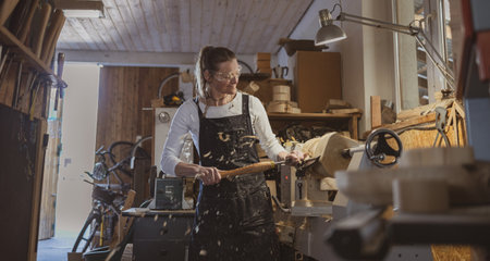 Portrait of mature woman working on a lathe in a workshopの写真素材