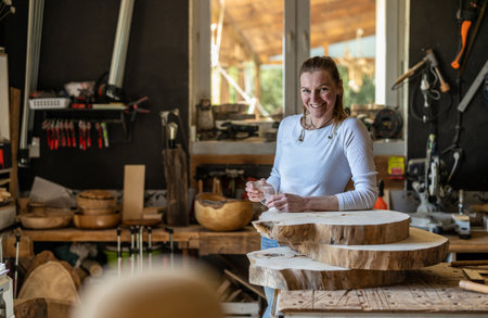 Portrait of a female carpenter in her workshop. She is smiling and looking at the camera.の写真素材