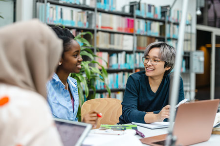 african american female teacher and students studying together in college libraryの写真素材