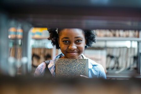 Portrait of smiling african american woman reading book in libraryの写真素材