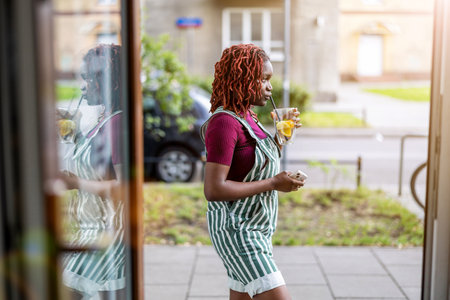 african american woman in striped apron holding ice cream and looking at shop windowの写真素材
