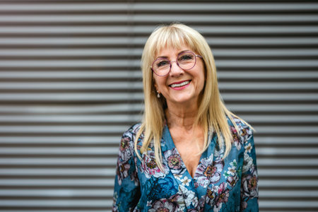 Portrait of a happy senior woman in eyeglasses standing outdoorsの写真素材