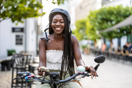 Portrait of happy african american woman in helmet riding bicycle in cityの写真素材