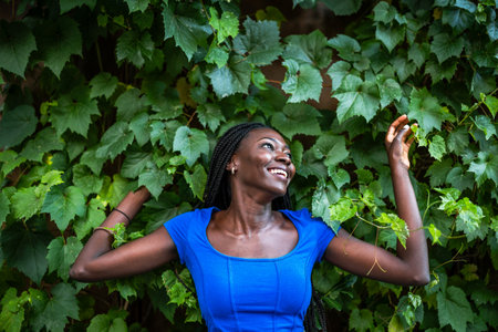 Beautiful young african american woman in blue dress posing in the garden.の写真素材