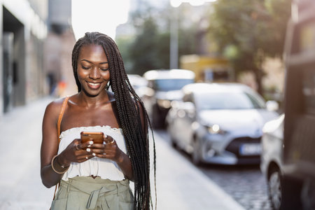 Portrait of young African woman using mobile phone in the cityの写真素材