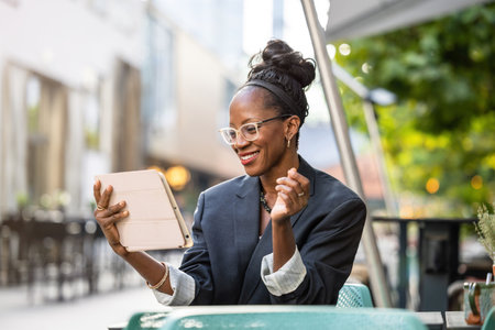 Portrait of happy african businesswoman using tablet in outdoor cafeの写真素材