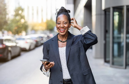 Portrait of happy african businesswoman using mobile phone in cityの写真素材