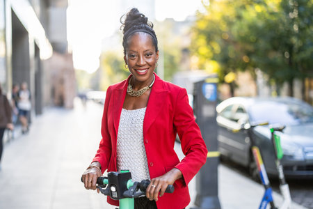 Beautiful african american businesswoman with electric scooter in the cityの写真素材