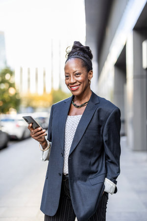 Portrait of a smiling African businesswoman using mobile phone outdoorsの写真素材