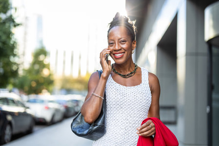 Portrait of a smiling African woman talking on mobile phone in the cityの写真素材