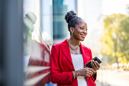 Portrait of a smiling african american businesswoman using mobile phone outdoorsの写真素材