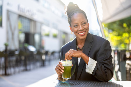 Portrait of happy african american businesswoman with healthy drink outdoorsの写真素材