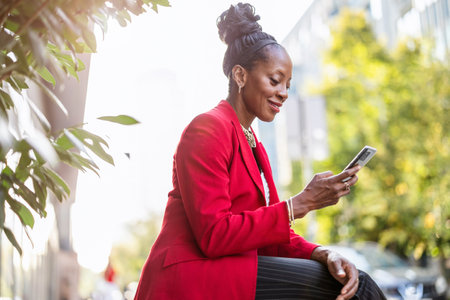 Portrait of a smiling young businesswoman using mobile phone in the cityの写真素材
