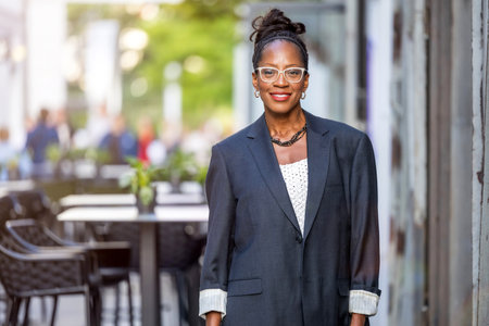 beautiful african american business woman in suit and eyeglasses standing outdoorの写真素材