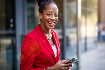 Portrait of a happy African businesswoman using mobile phone outdoorsの写真素材