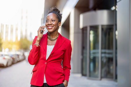 Portrait of a smiling African businesswoman talking on mobile phone outdoorsの写真素材