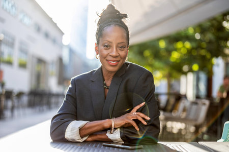 Portrait of a smiling businesswoman sitting at a coffee shop outdoorsの写真素材