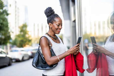 Portrait of happy african american woman using mobile phone in cityの写真素材