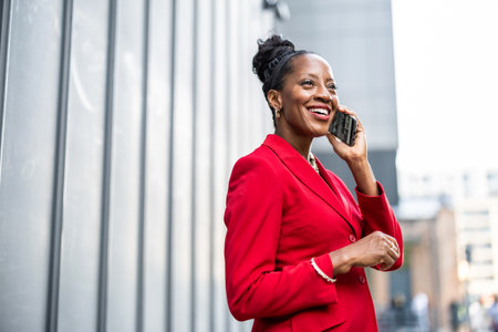 Portrait of smiling african american businesswoman talking on mobile phone outdoorsの写真素材
