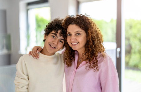 Portrait of smiling mother and son standing in living room at homeの写真素材