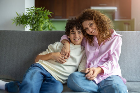Portrait of mother and daughter sitting on sofa at home in living roomの写真素材